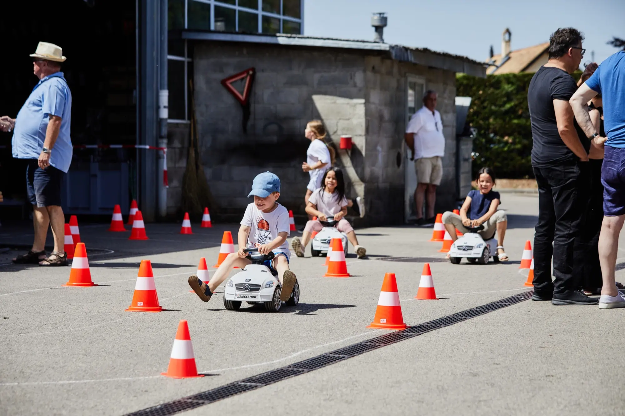 Des enfants au volant de petites voitures entre des cônes, pendant les 100 ans du Garage Grin.