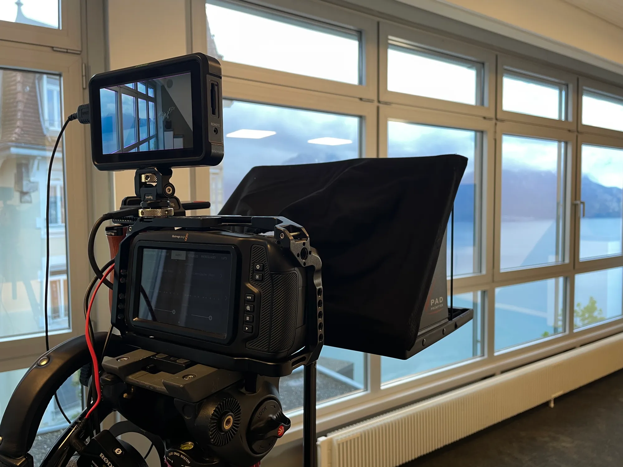 A camera fitted with a teleprompter, set up in a meeting room.