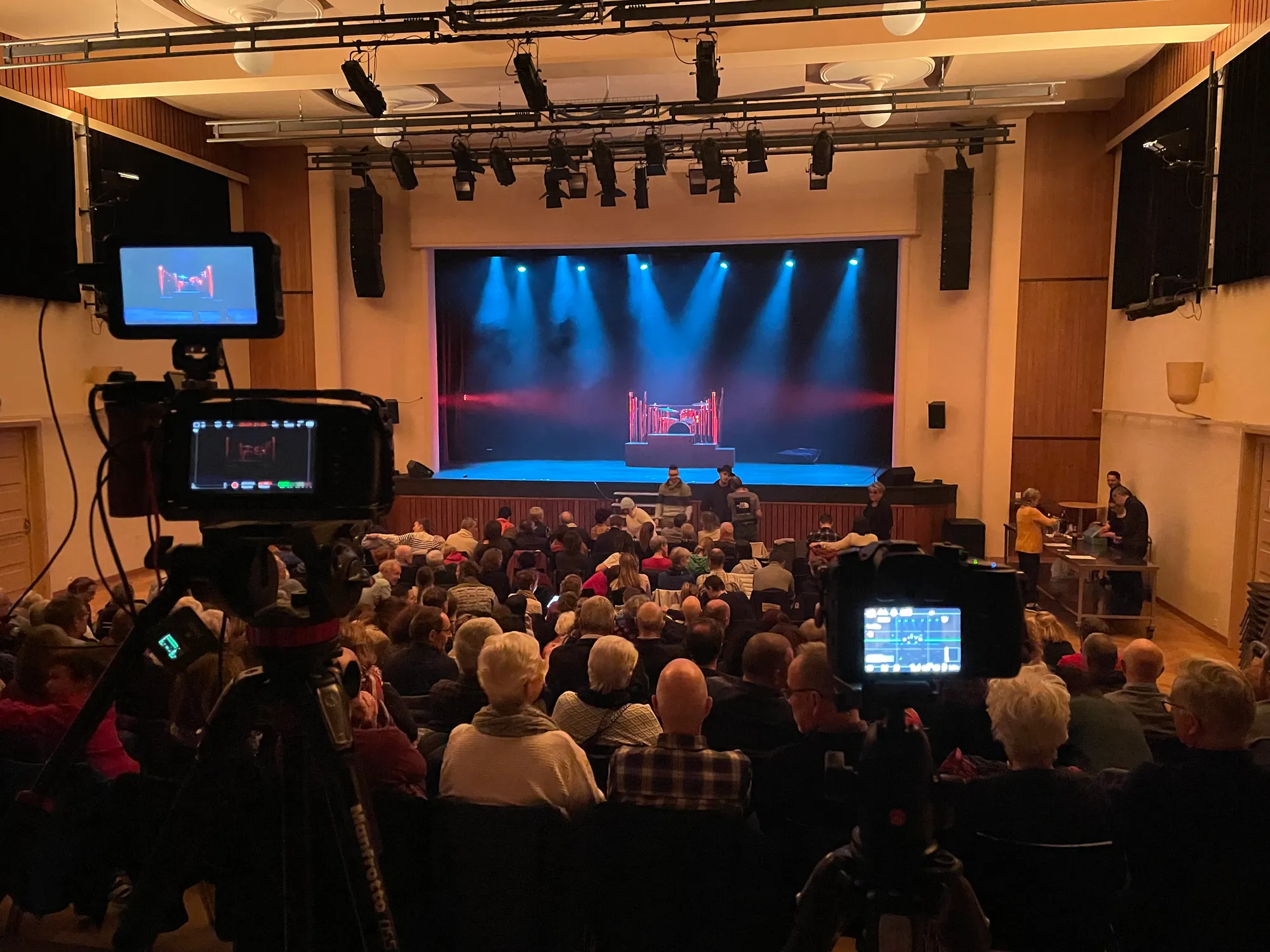 Cameras placed behind the audience, during a performance in a full hall.